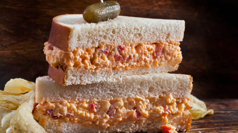 Stack of sliced pimento cheese sandwich on a wooden table