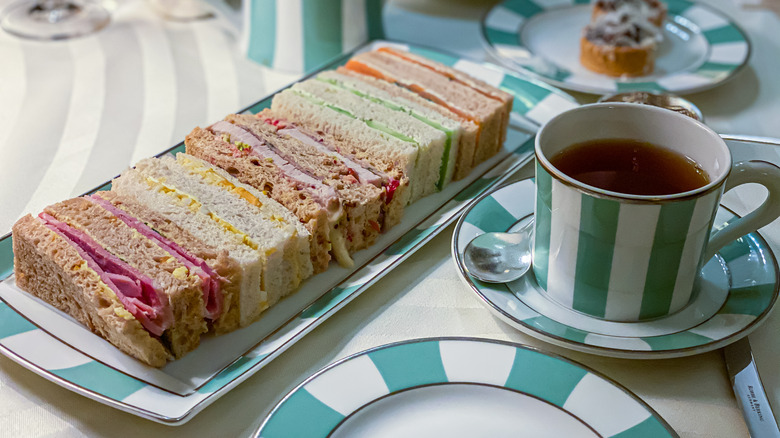 Variety of tea sandwiches next to cup of tea