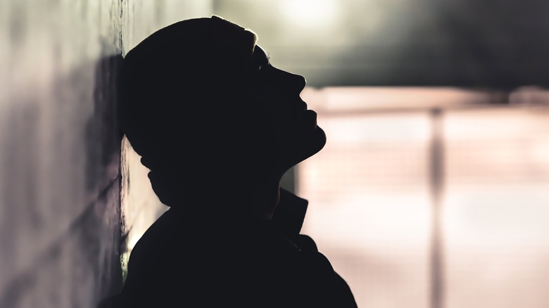 Male in silhouette leaning against wall