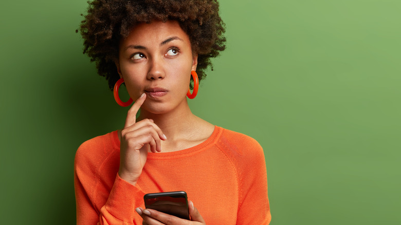 Woman thinking and holding phone