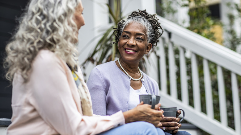 Two women enjoying cups of coffee while sitting on steps