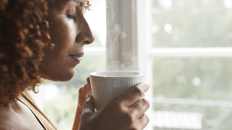 A woman enjoying the smell of her fresh cup of coffee