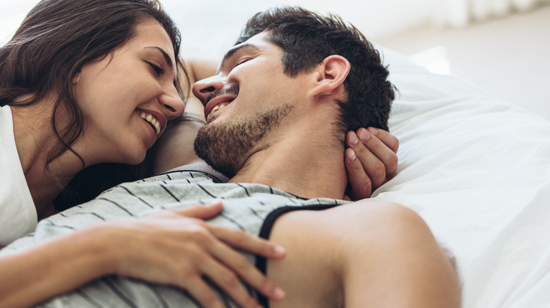 Couple smiling at each other in bed