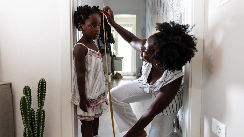 Mother measuring height of child