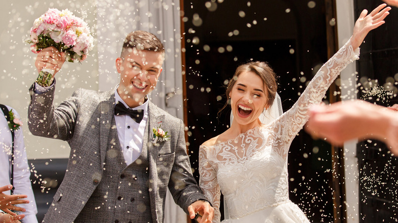 Couple leaving wedding with guests throwing rice