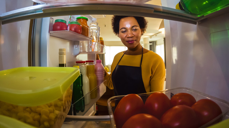smiling woman taking food out of a refrigerator