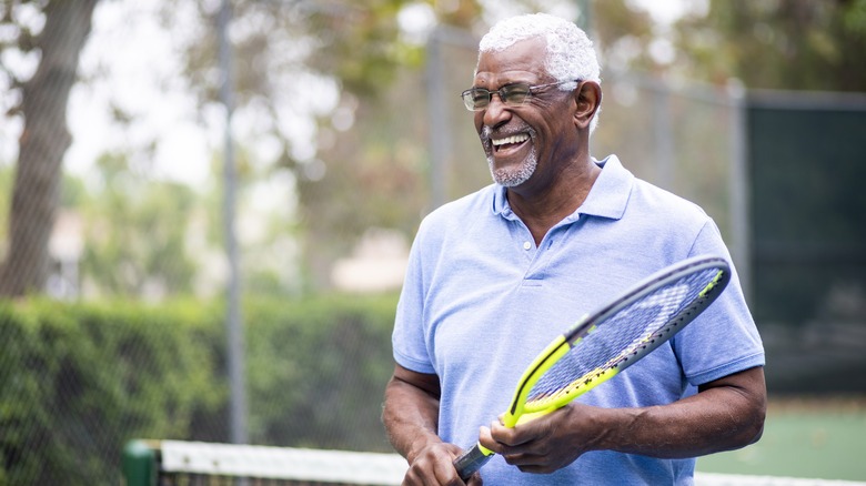 Man with tennis racket smiling