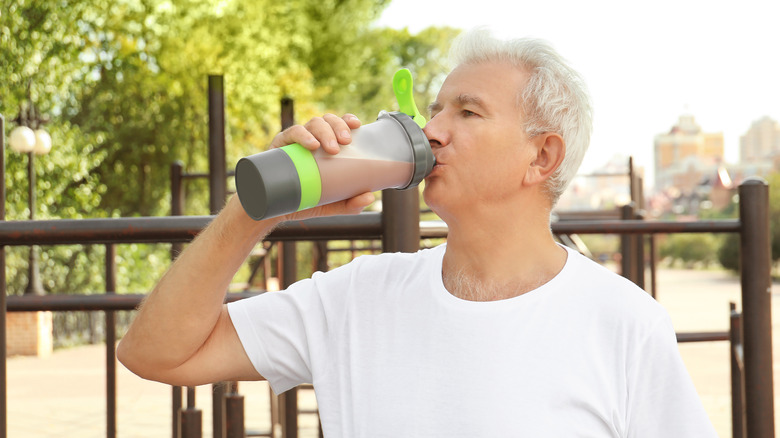 A senior man drinks a protein shake