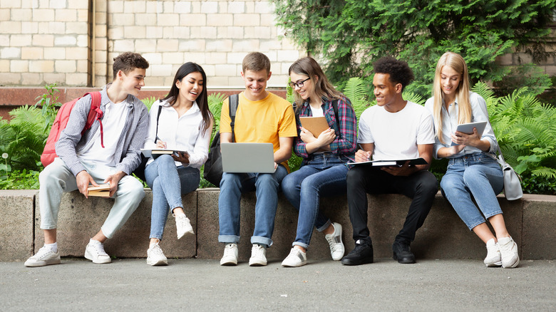 Group of teens sitting together with backpacks on a college campus