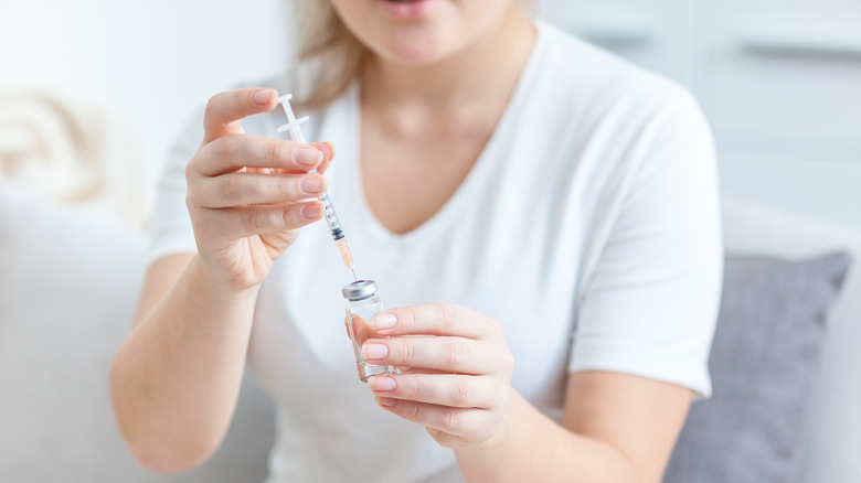 Woman filling syringe from insulin vial