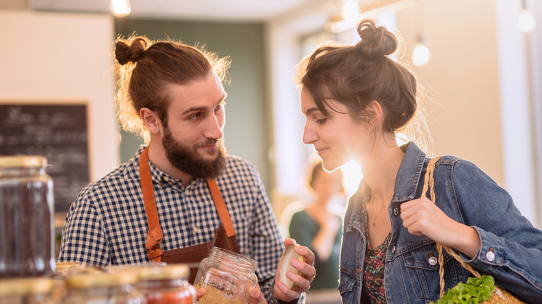 younger woman buying bulk food from adult male