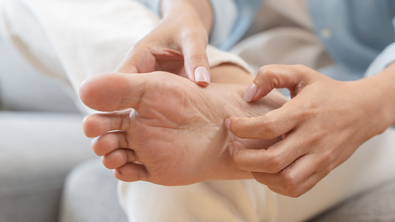 A close-up of a hand scratching itchy, bare feet