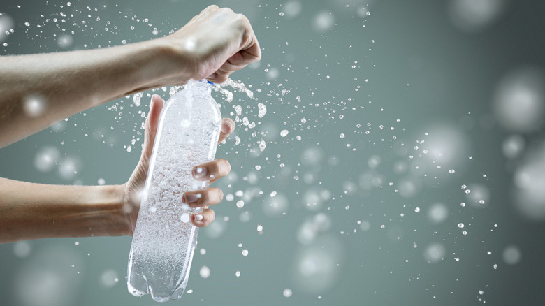 Hands opening a seltzer bottle