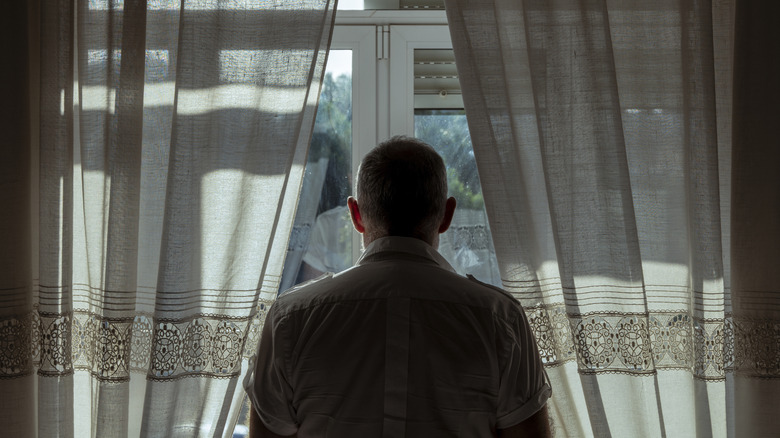 man looking out window from behind