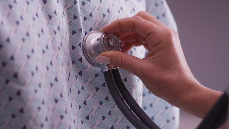 hand holding stethescope on patient chest