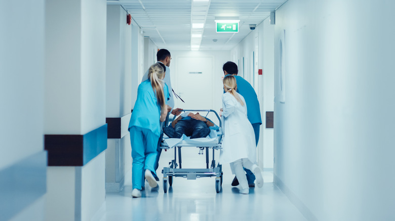 Medical personnel wheeling a patient down a hall on a gurney