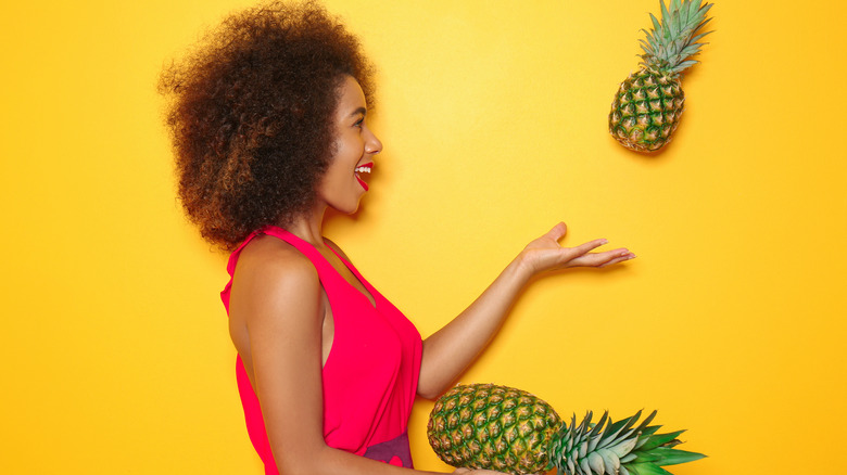 Woman tossing pineapple