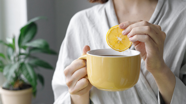 Woman holding coffee cup and lemon slice