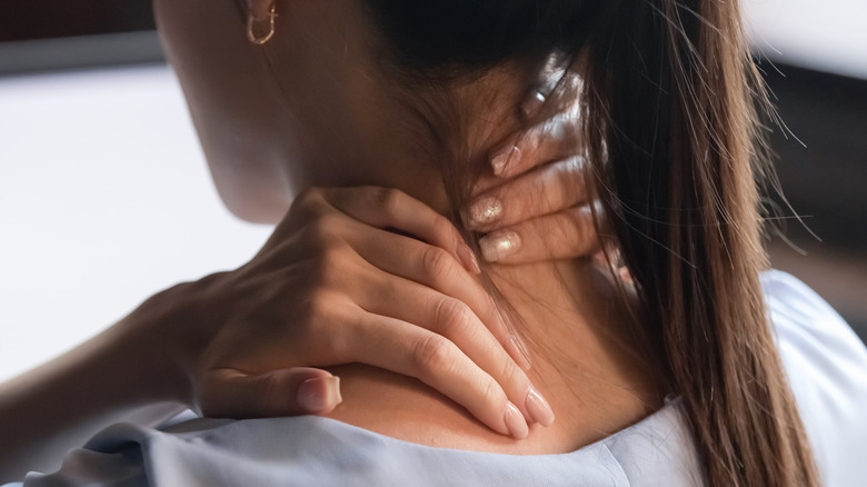 Woman massages back of neck