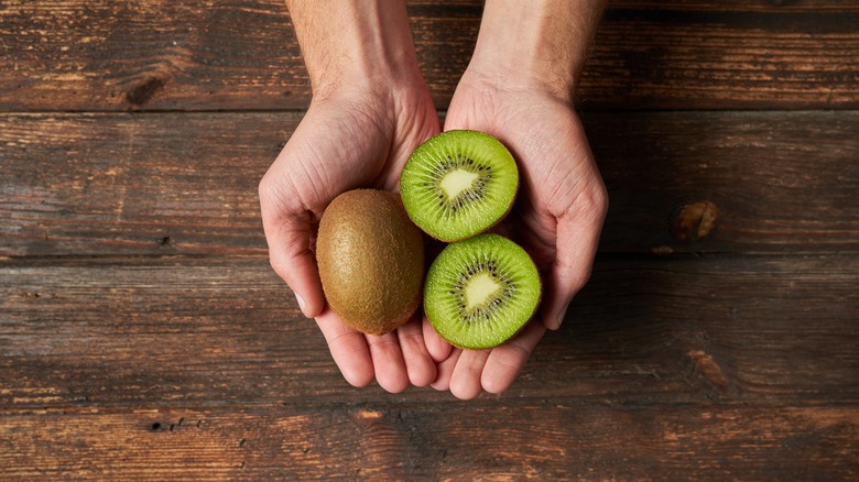 person holding kiwis in hands