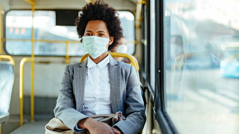 Young business woman wearing a surgical mask while riding a public bus