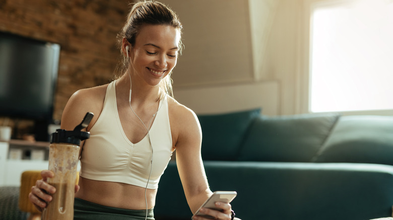 Woman enjoying protein shake while on phone