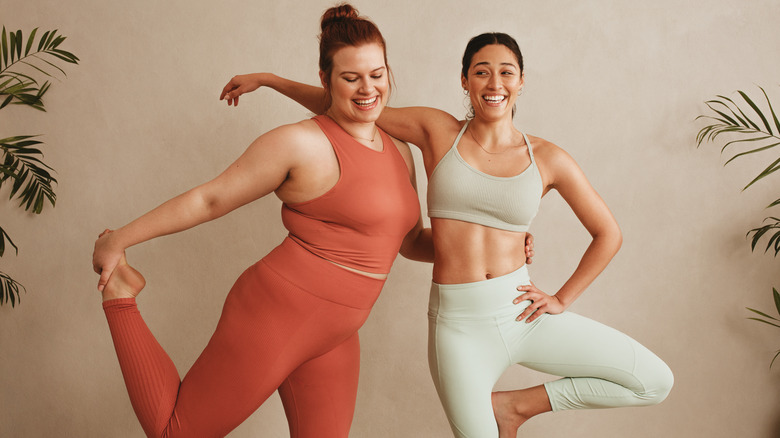 two ladies laughing and stretching together 