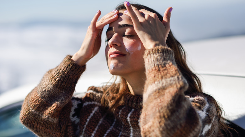 Woman applying sunscreen on her face and hairline