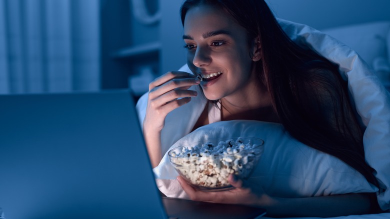 Woman eating popcorn in bed 