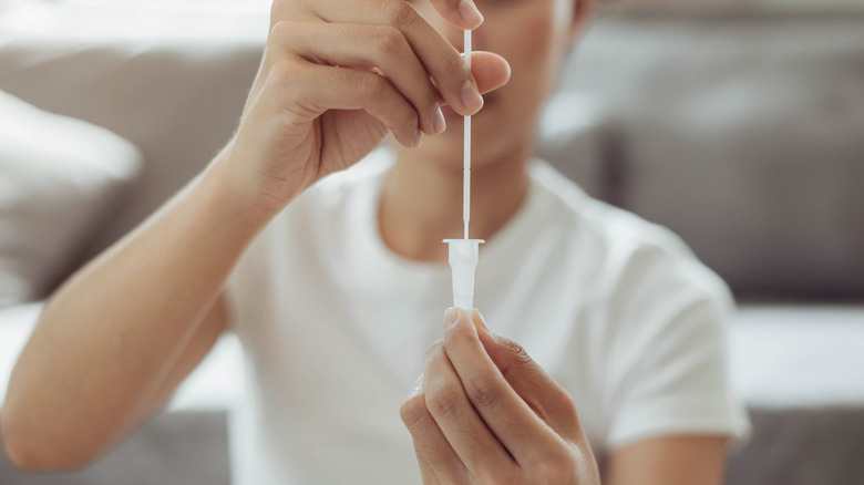 Person placing a COVID-19 test swab into a vial