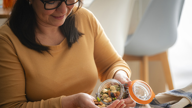 woman pouring handful of nuts into hand for snack