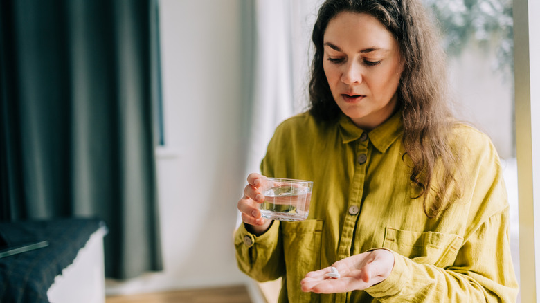 woman taking a pill with water