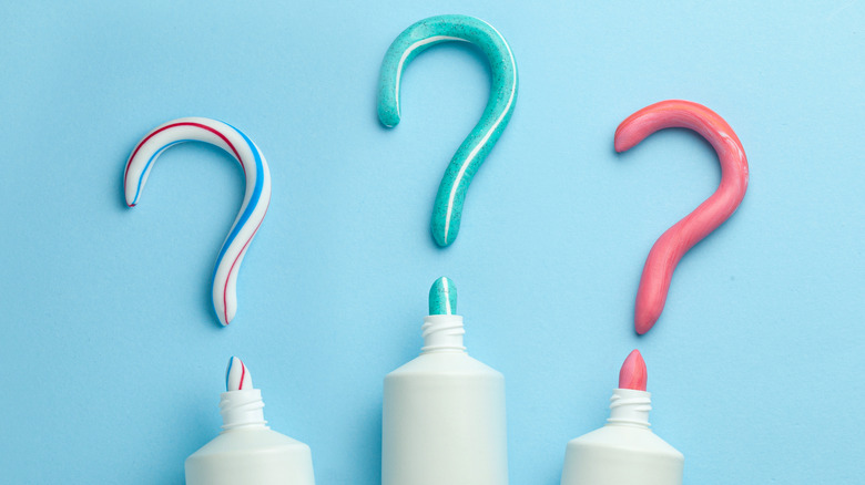 three tubes of toothpaste with toothpaste forming question marks