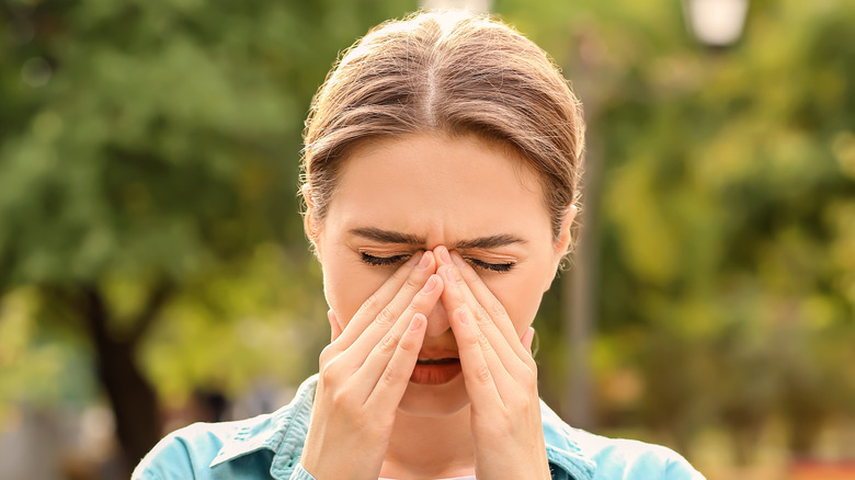 Young woman suffering from allergy outdoors