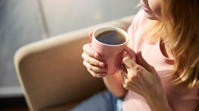A woman drinks a cup of coffee