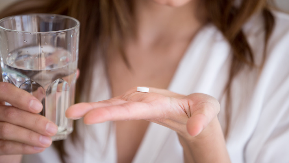Woman holding water and pill