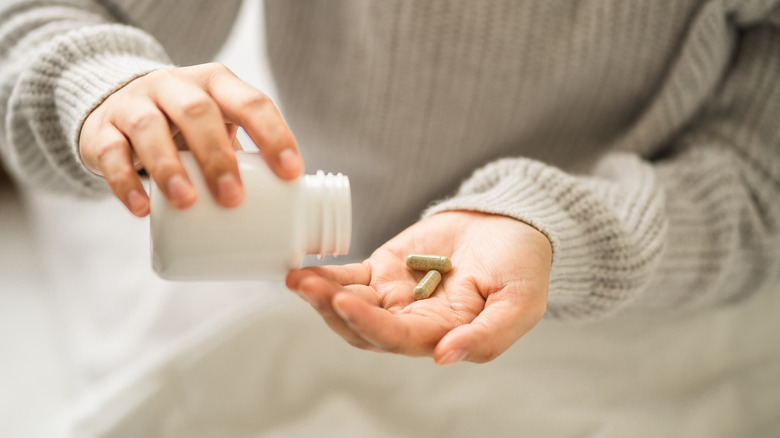 Someone takes a handful of pills