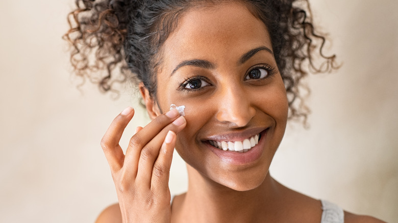 woman applying skin cream on face