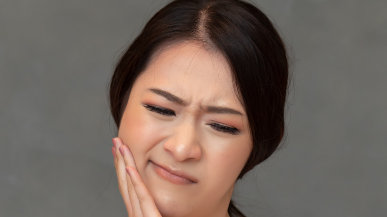 woman holding hand on cheek in pain