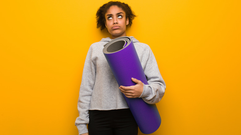 Bored woman holding yoga mat