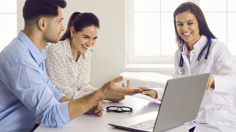 Doctor teaching couple using laptop