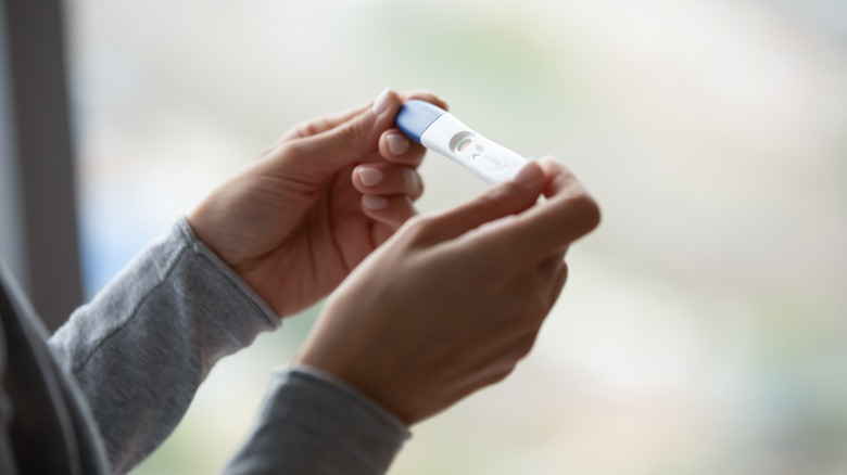 woman's hands holding pregnancy test