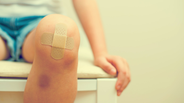 Close up of child with bruised and cut knee with bandage