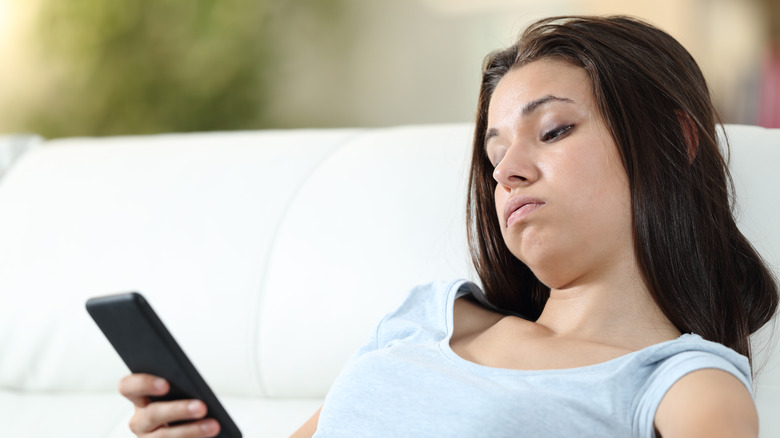 woman sighing looking at smartphone 