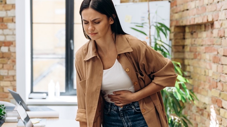 woman experiencing stomach pains at her desk