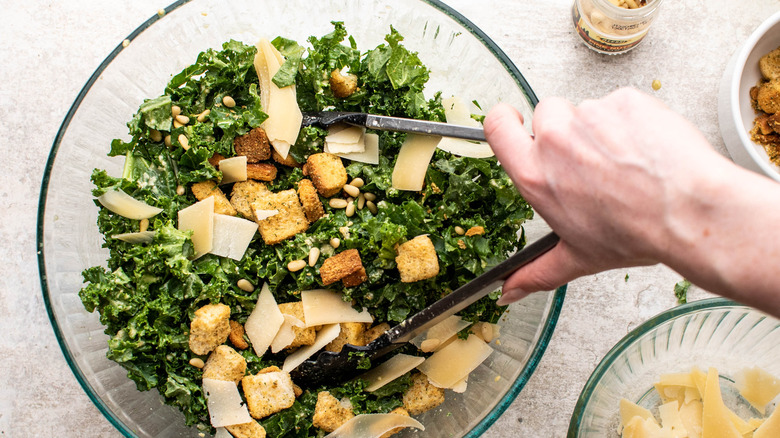 tossing caesar salad ingredients together