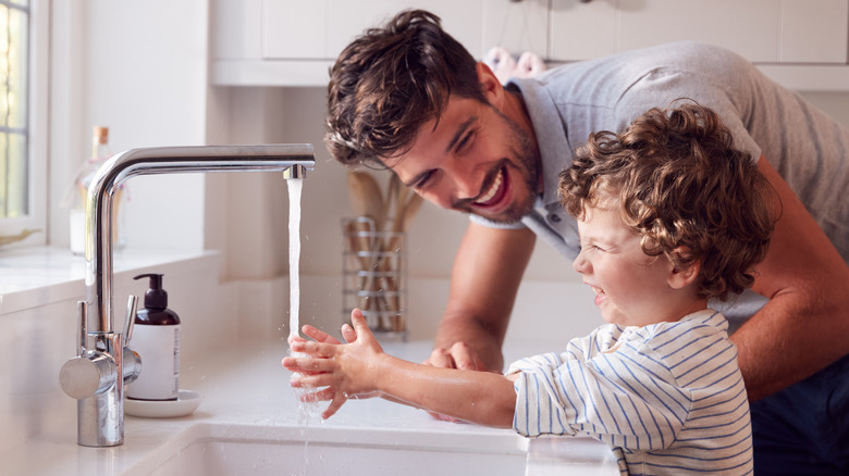 man teaching boy to wash hands