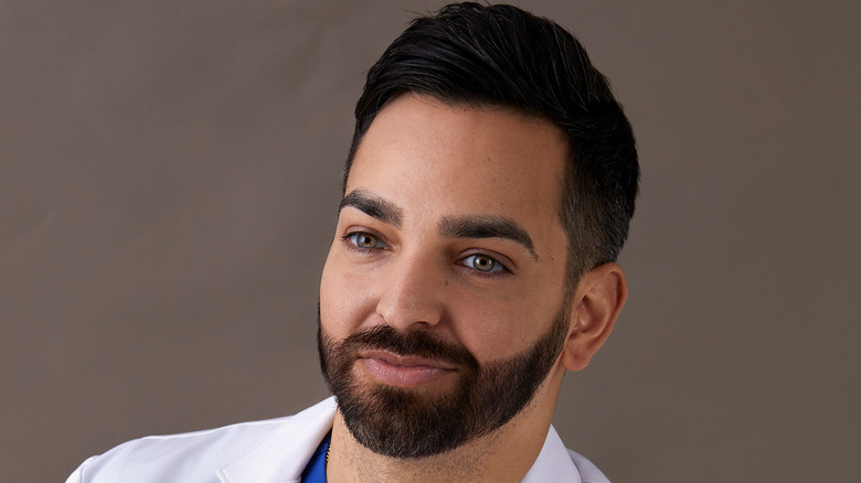 Close up picture of Dr. Muneeb Shah in blue scrubs and his lab coat