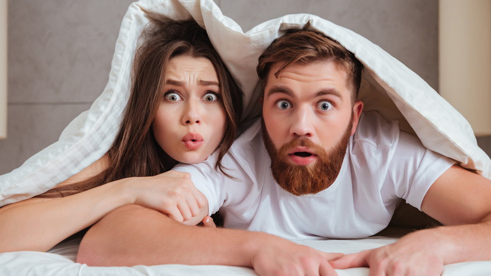 man and woman looking surprised in bed