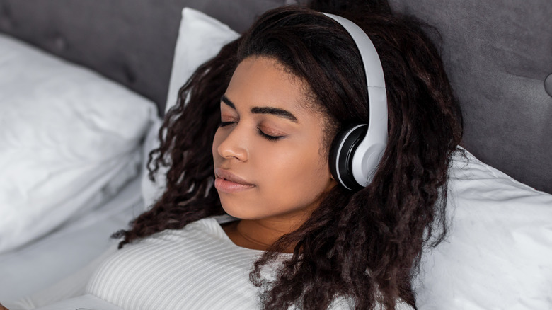 Woman sleeping in bed with headphones on